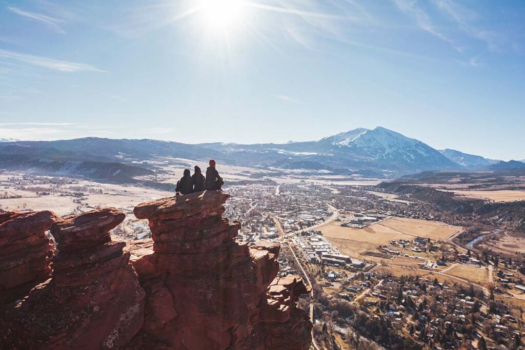 Distant view of women sitting on large rocks overlooking the mountains