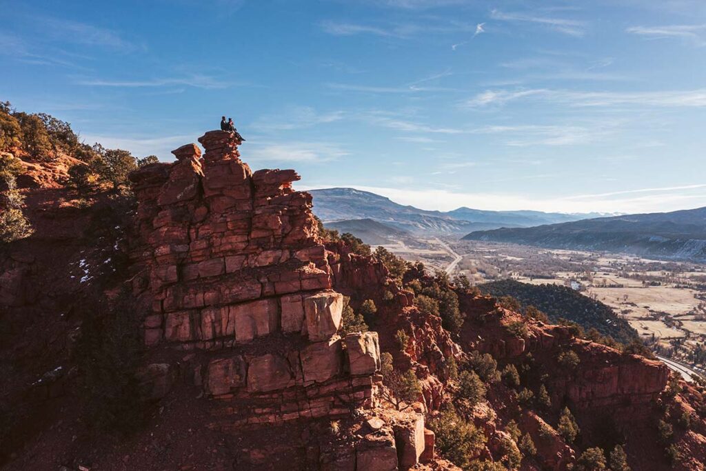 Distant view of women sitting on large rocks overlooking the mountains