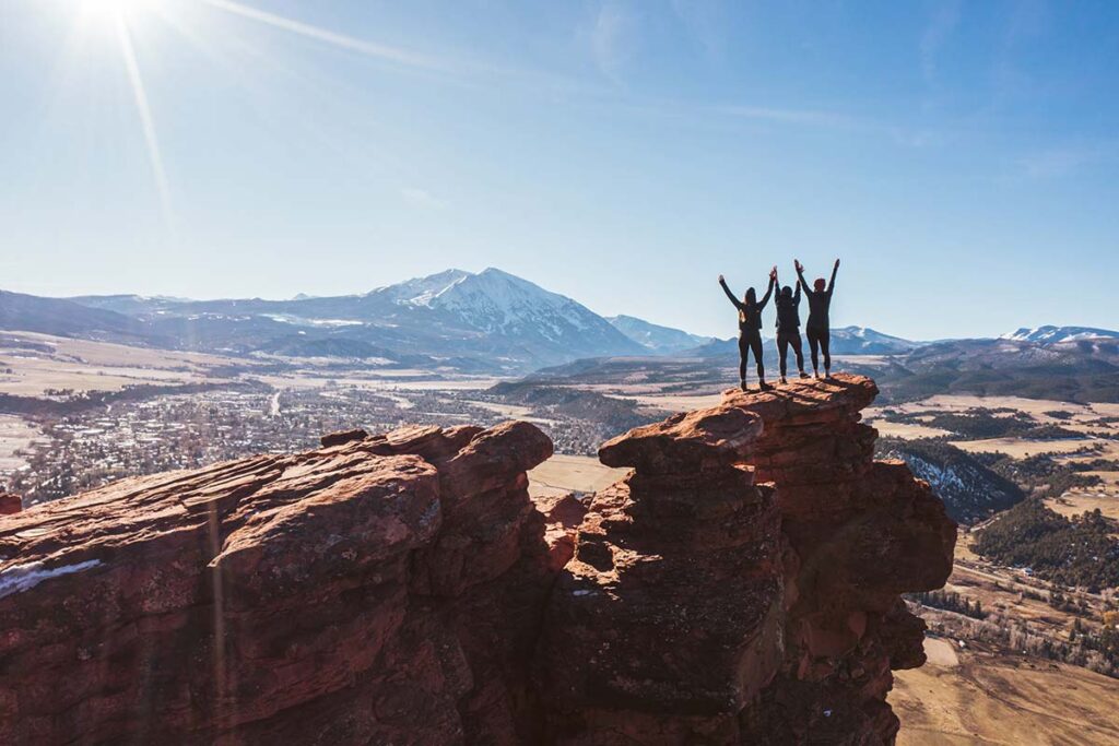 Women with arms raised in victory in front of mountains