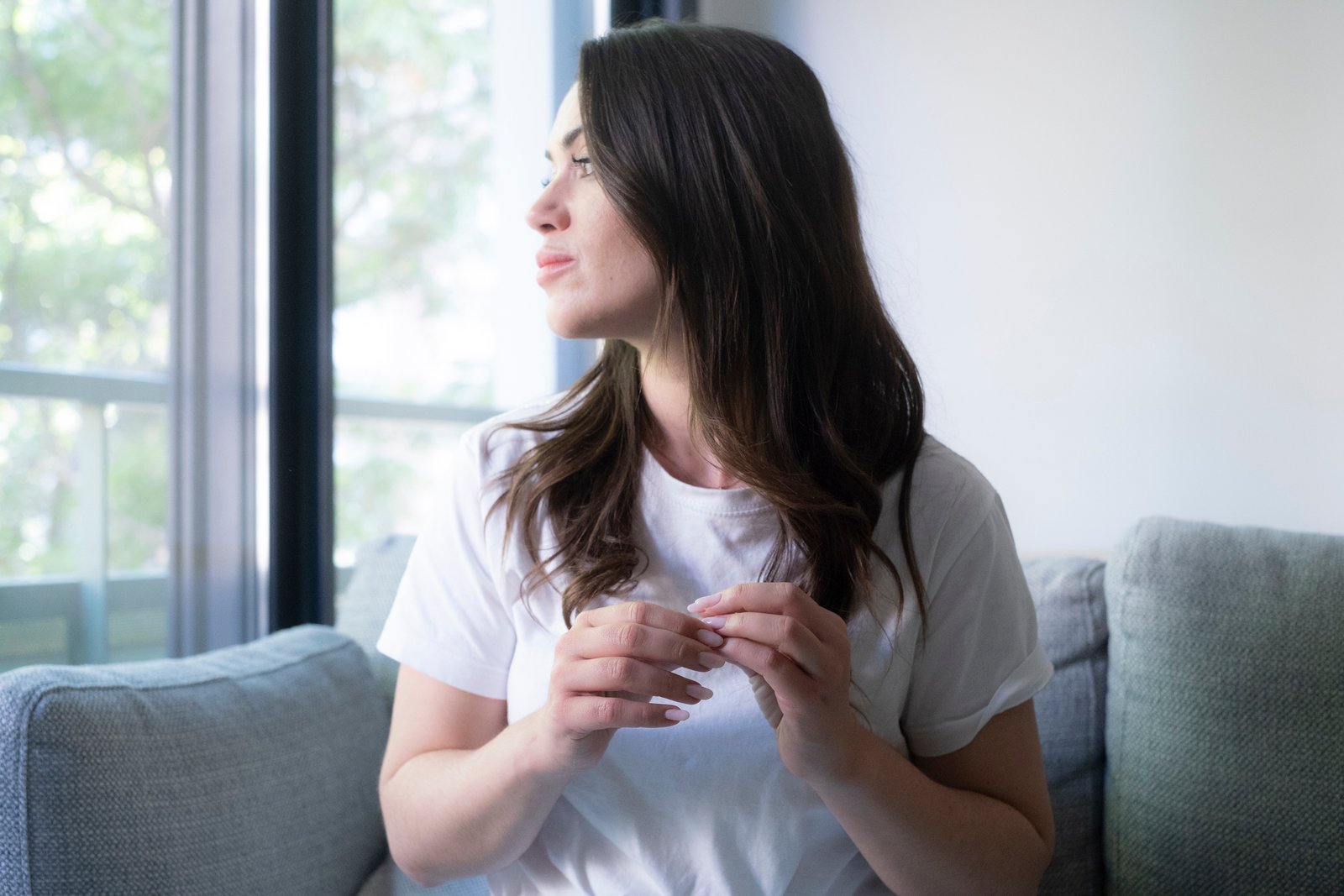 Woman sitting by a window at home looking thoughtful and reflective