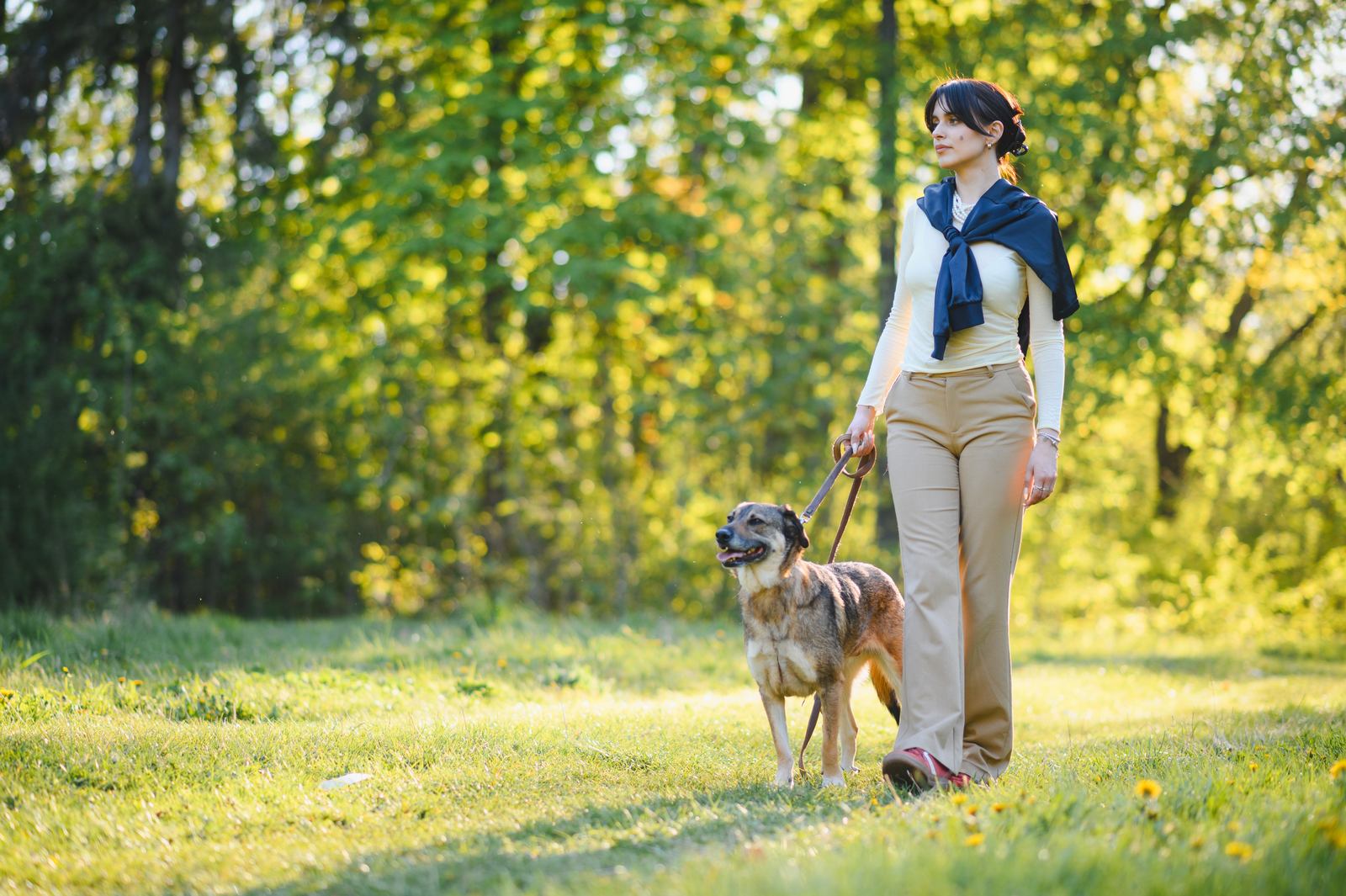 A woman walking her dog outdoors in a sunlit park, reflecting holistic wellness at a women's alcohol rehab in Colorado.