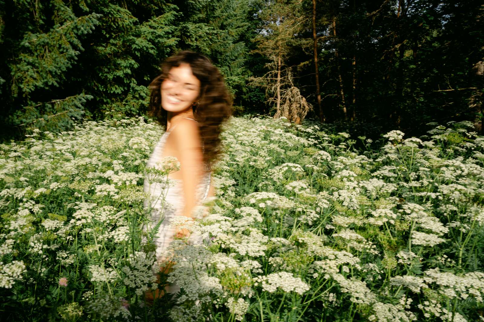 A woman smiling joyfully in a sunlit wildflower meadow, representing hope and recovery for women at an alcohol rehab in Colorado.